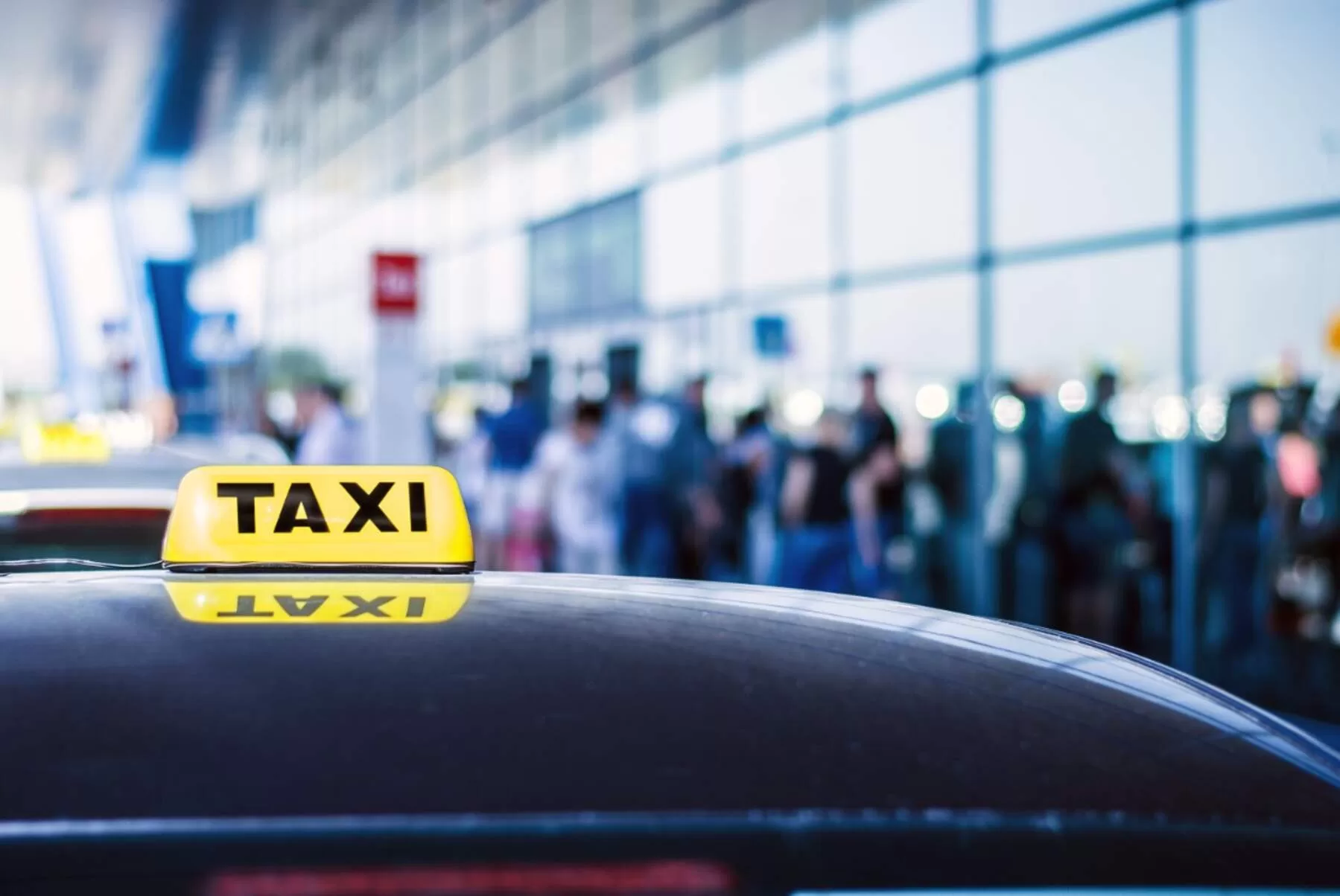 Taxi outside the airport with people in the background.