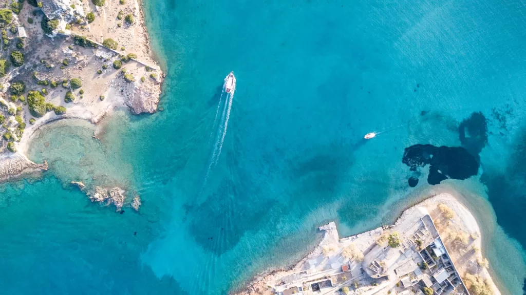 Aerial view of a beach and sea with boats transporting tourists in a coastal area.